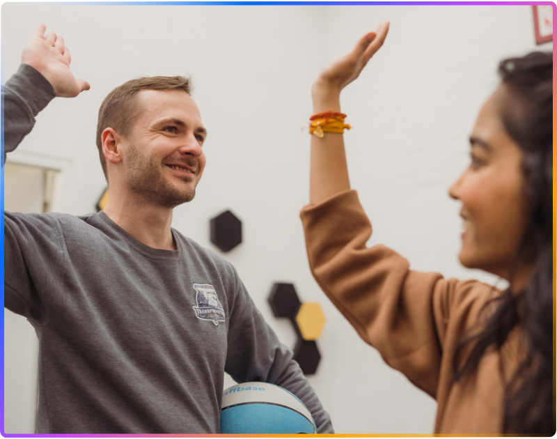 Two people standing across from each other giving each other a highfive.